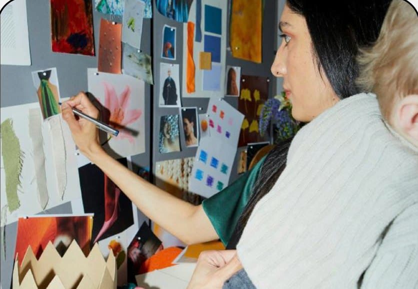 A designer pinning looks to a moodboard wall